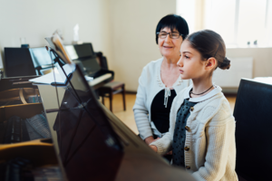 Girl playing piano with teacher